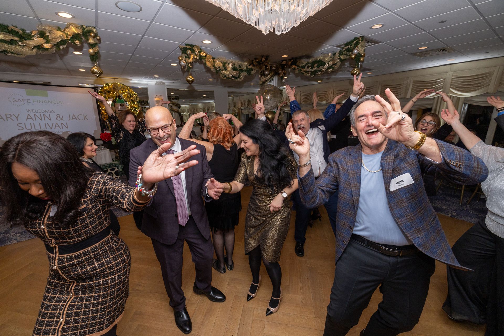 People dancing at a party; festive decorations. Joyful expressions; indoors.