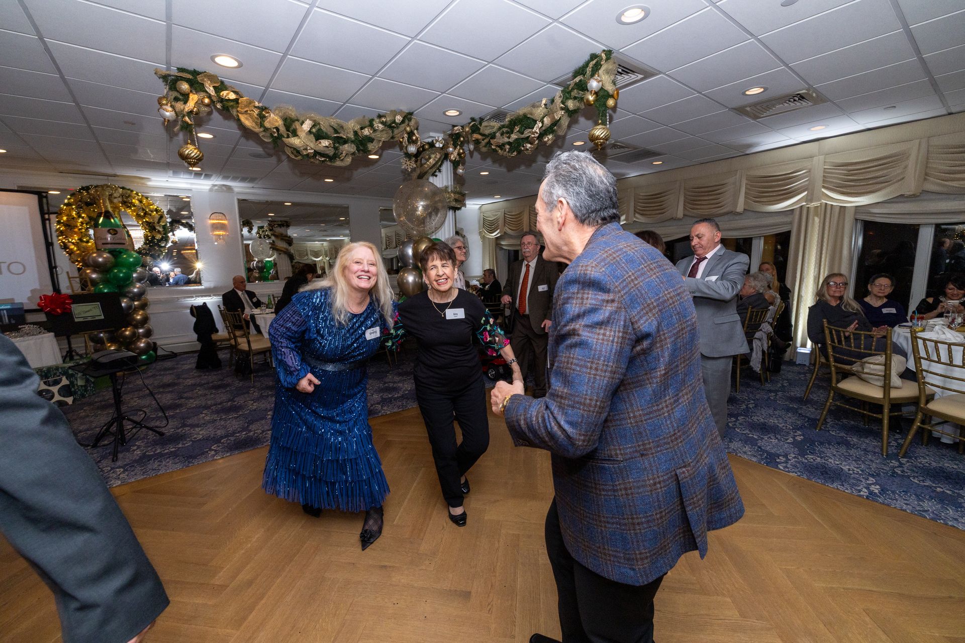 People dancing at an event, festive decorations above.