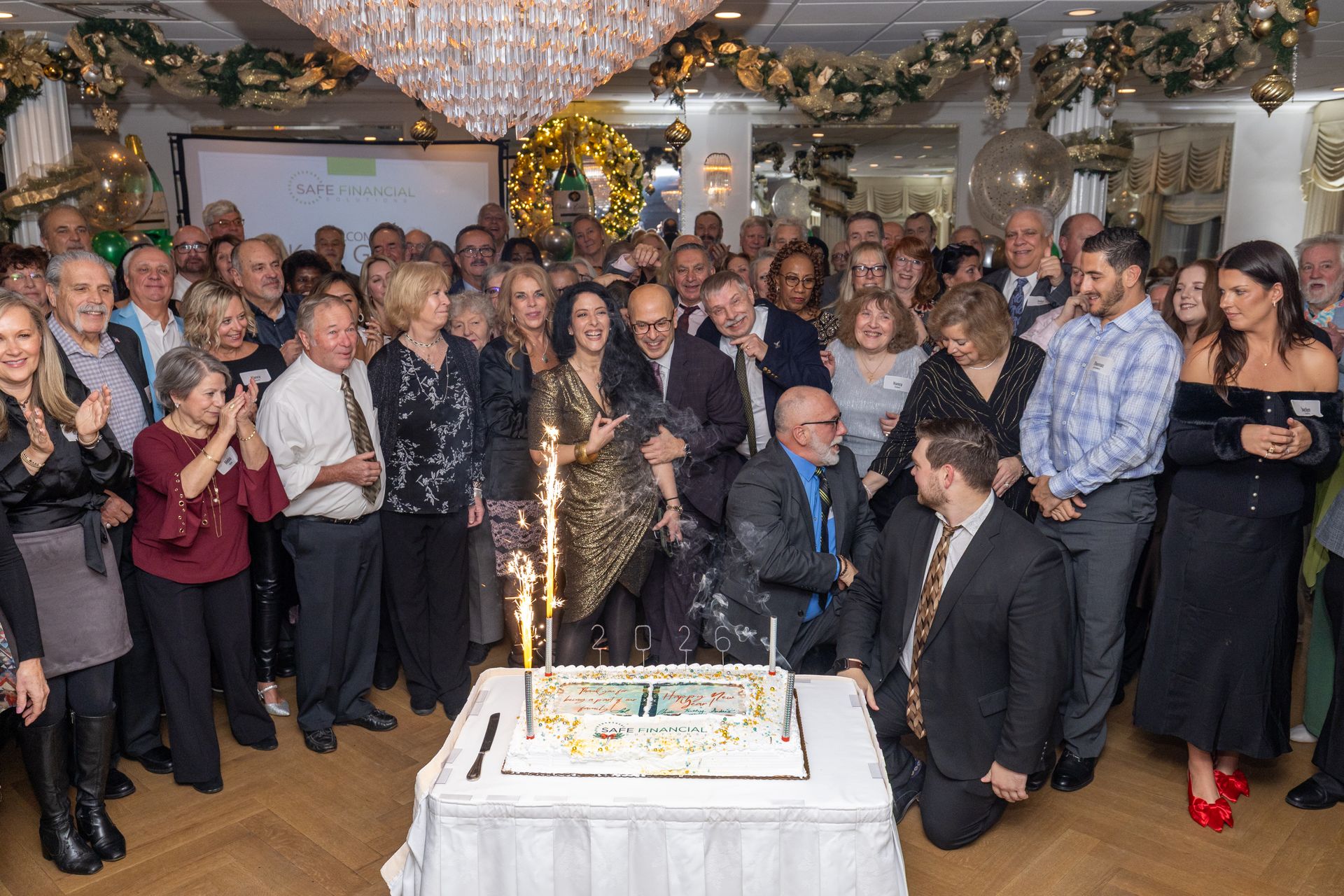 Group of people celebrating around a cake with sparklers. Party setting with decorations.