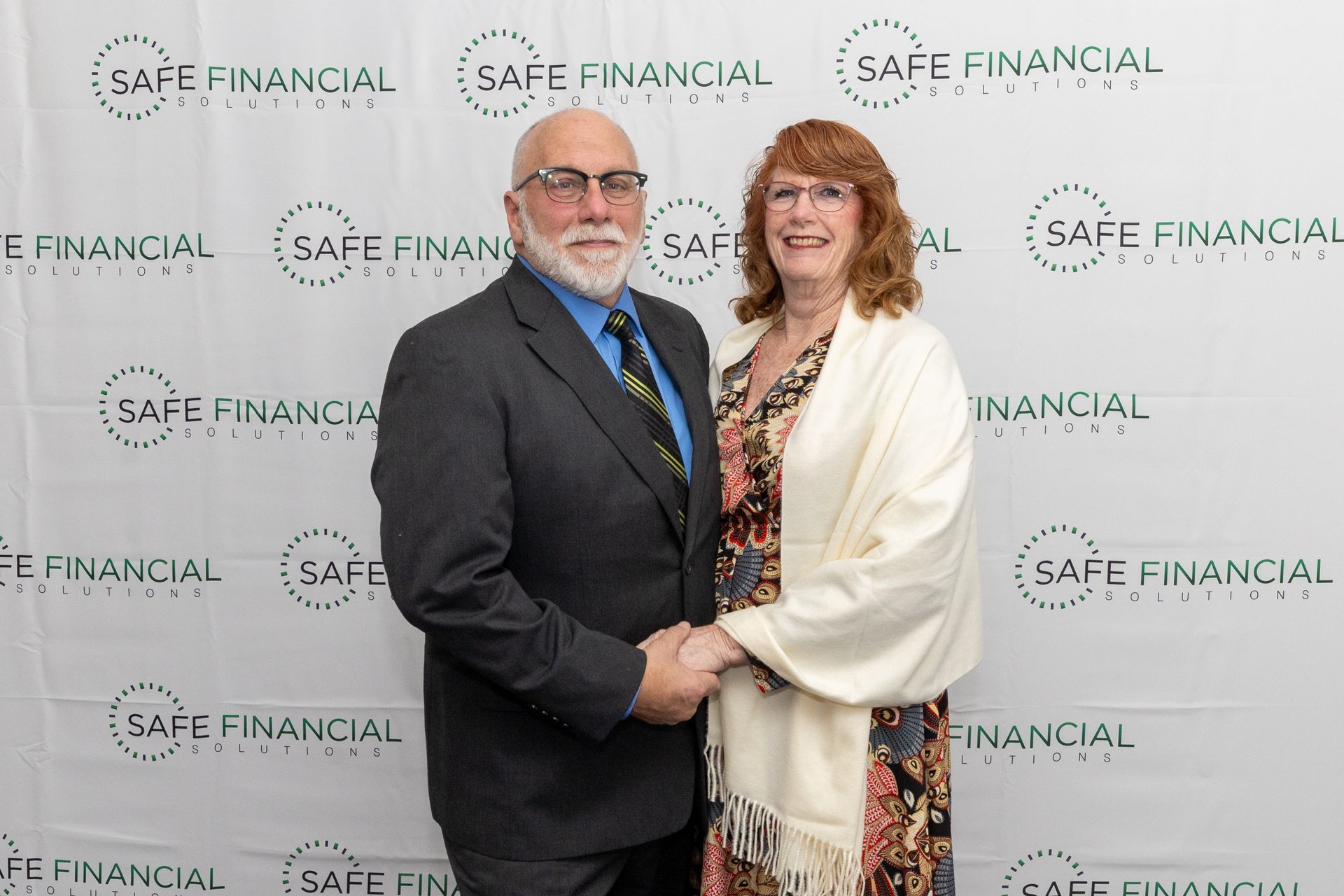 Couple holding hands posing in front of a backdrop with 