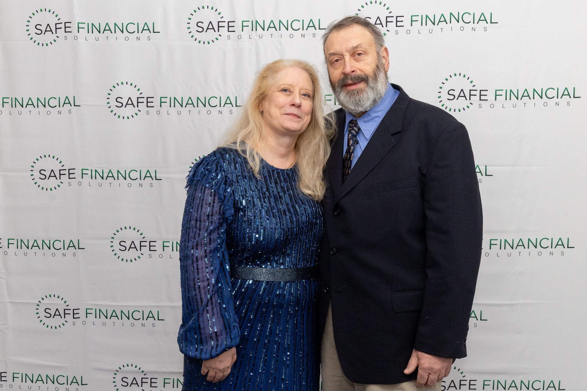 A couple posing in front of a backdrop with the words 