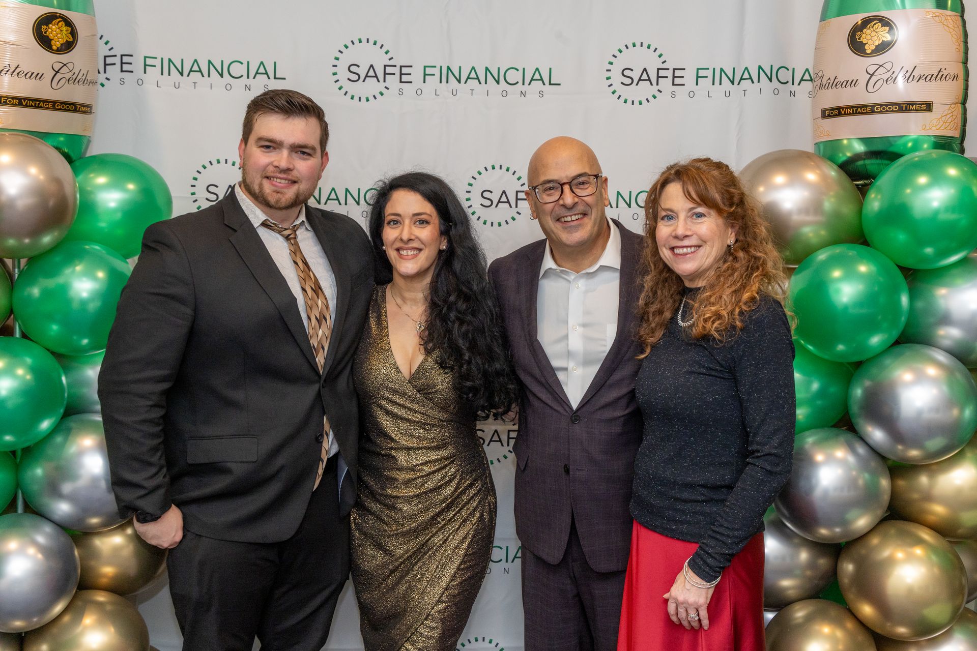 Four people posing in front of a balloon wall at a 