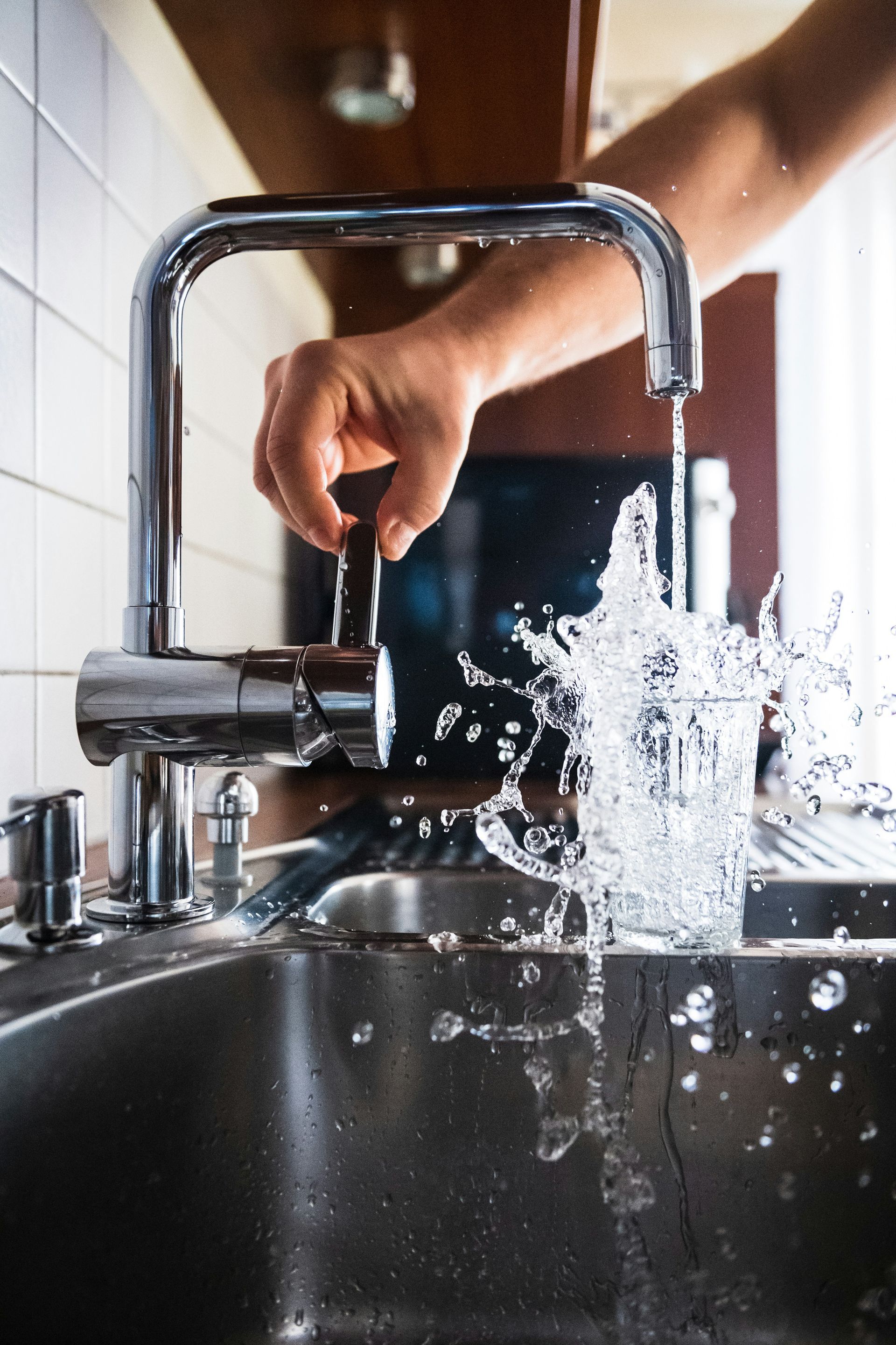 Hand rinsing a black pot in a kitchen sink under running water