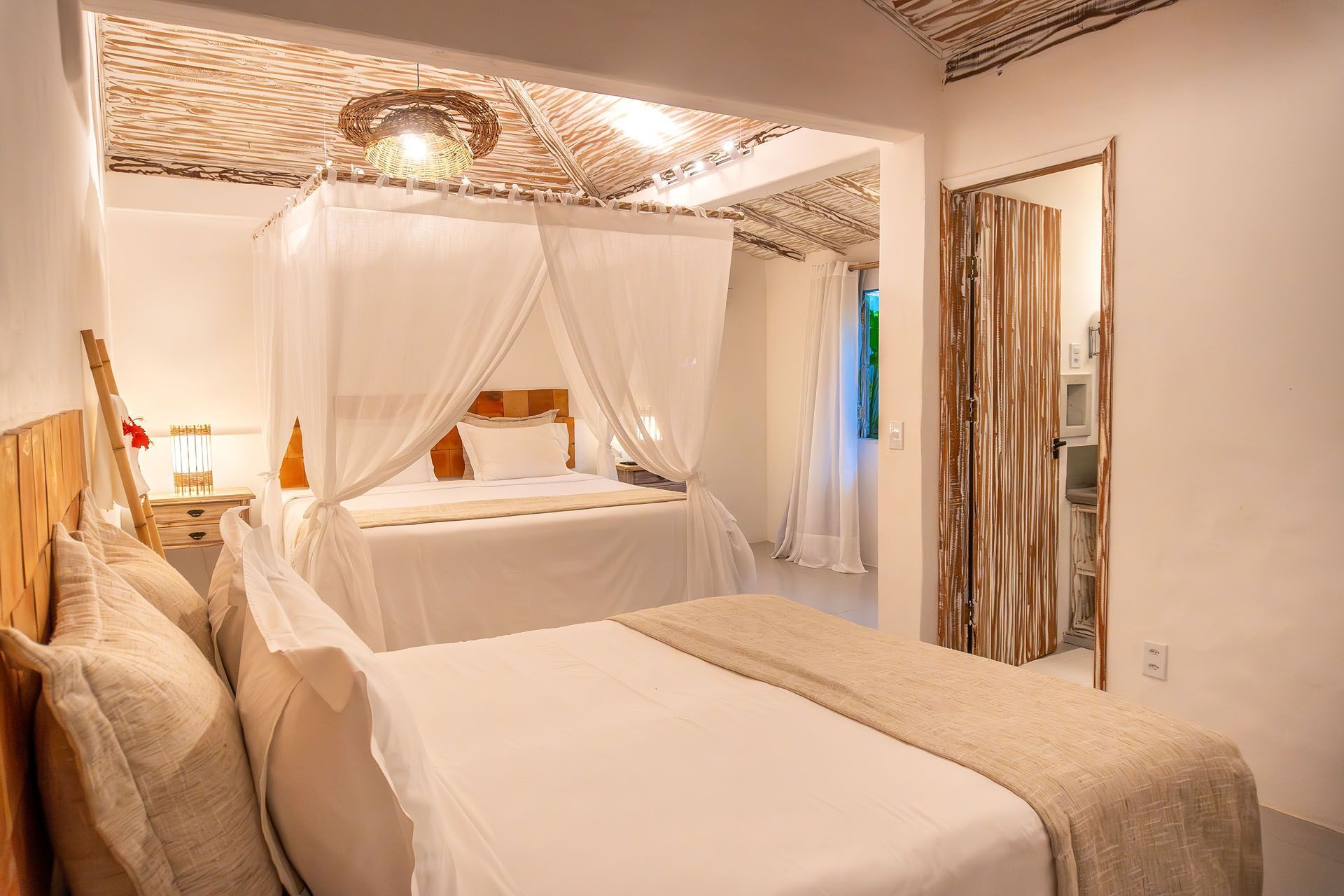 Quarto luminoso com cama de dossel, roupa de cama bege, parede espelhada e iluminação decorativa aconchegante.