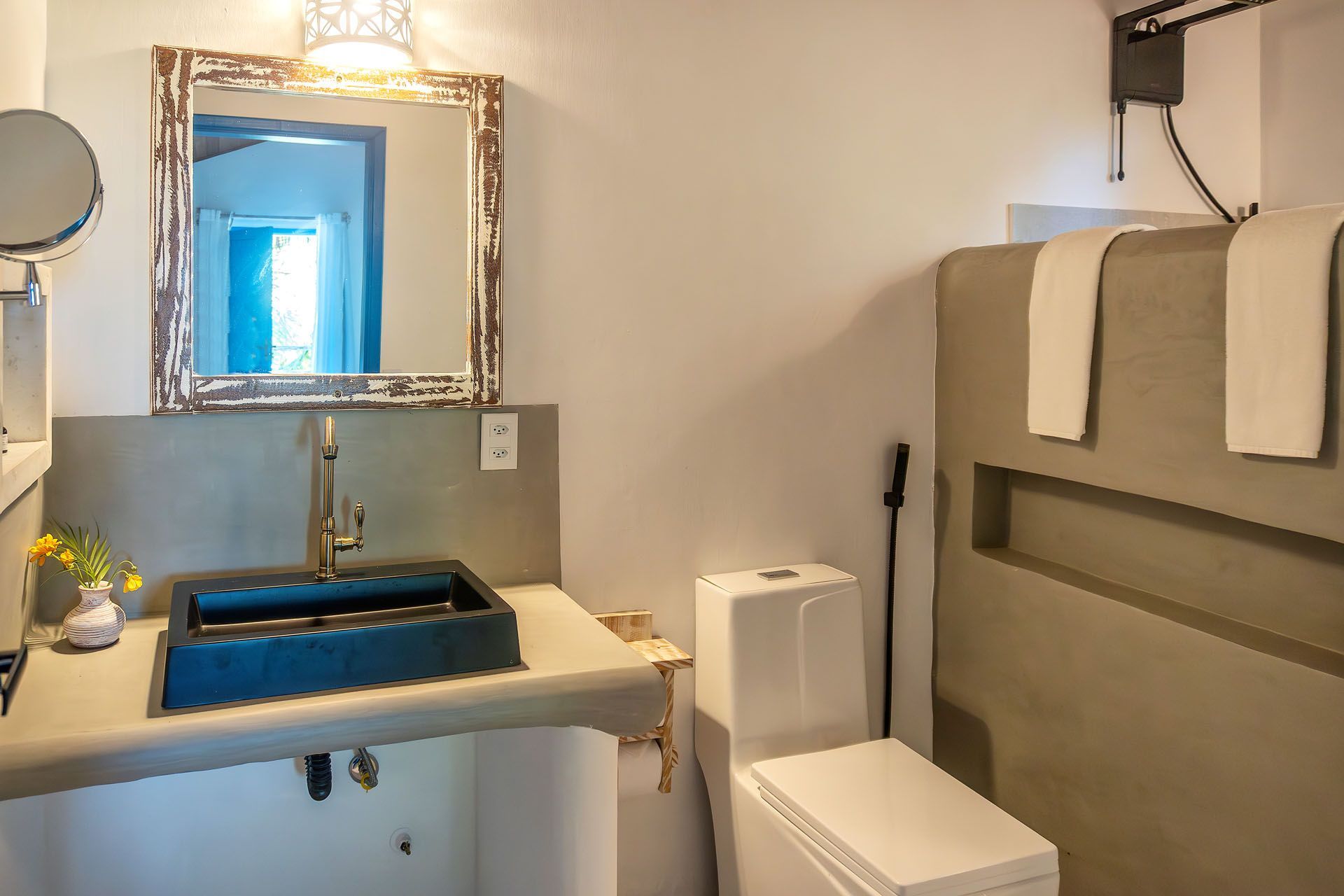 Banheiro moderno com pia azul, espelho, vaso sanitário e porta-toalhas acima da banheira.