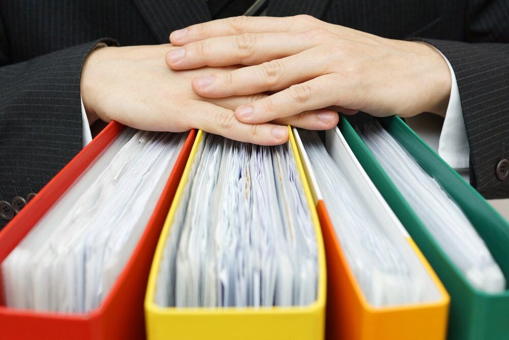 Person's Hands Resting on Three Ring Binders Filled With Documents — NR Bookkeeping in Bangalow, NSW