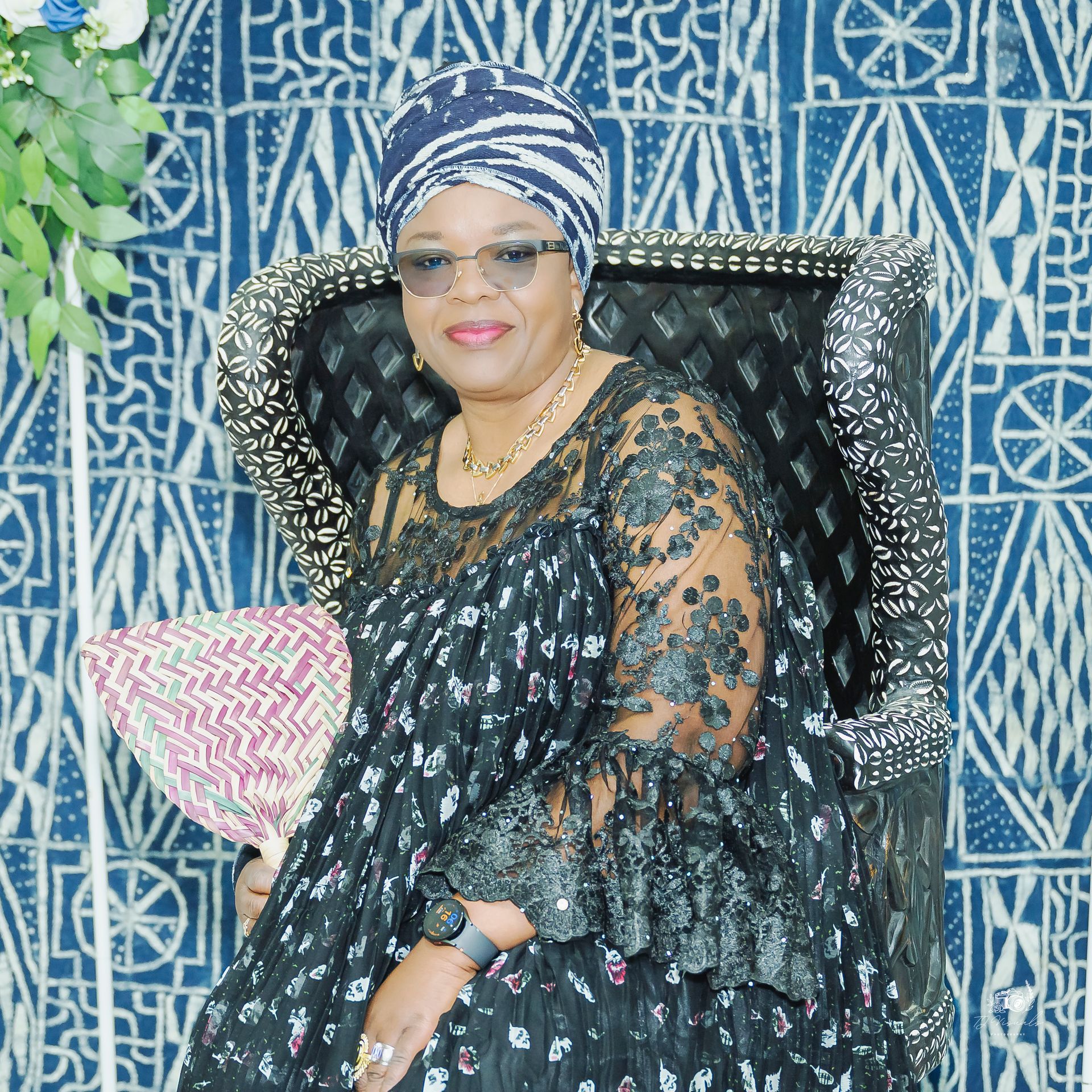 Two people filming an event with cameras on tripods. One sits, the other stands. Blue background, blurry crowd.