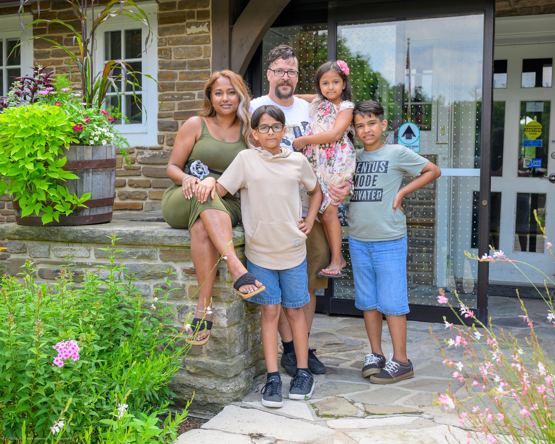 Family of four posing on steps; man in red pants, woman in pink, two children.