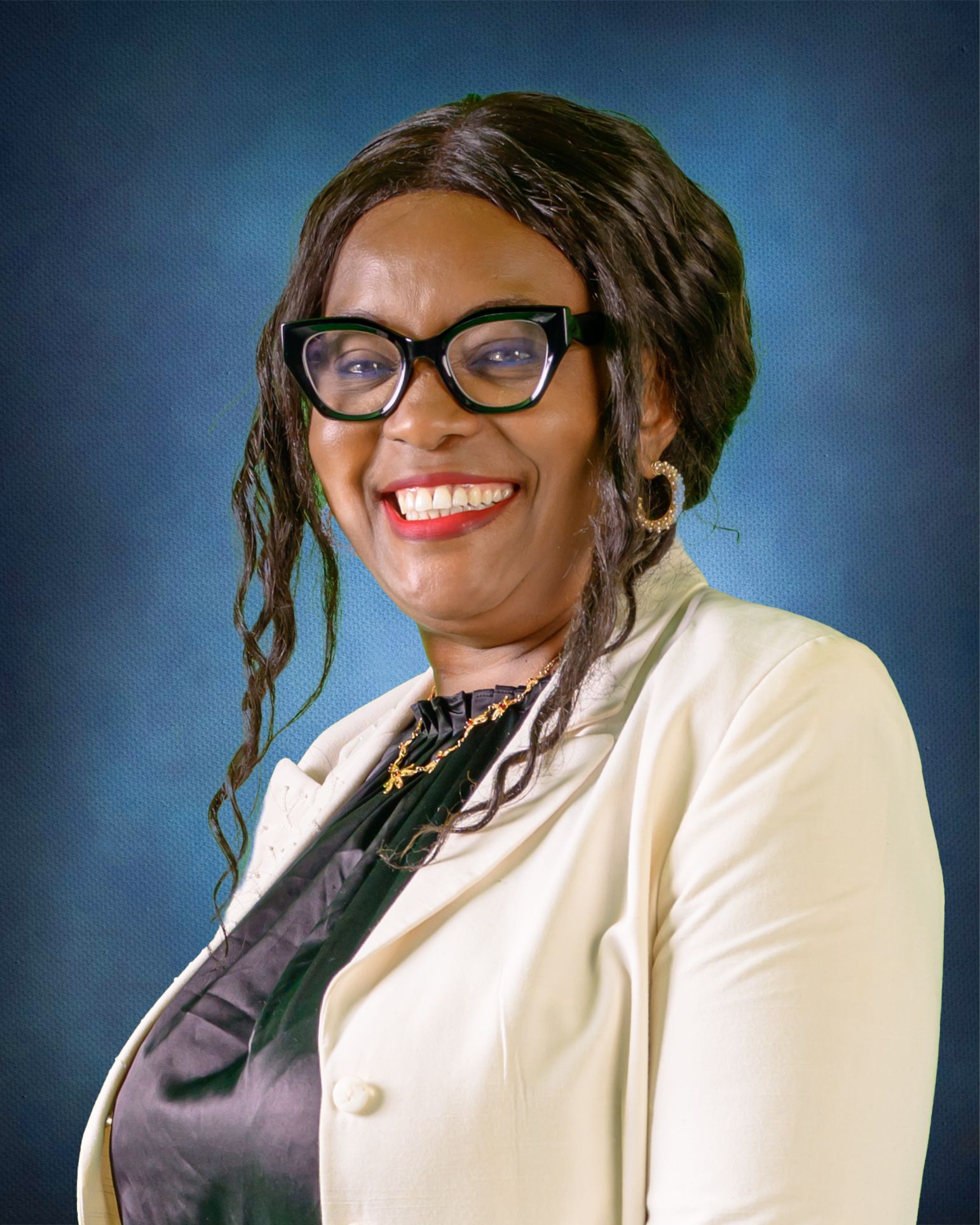 Woman with glasses, smiling, wearing a cream blazer and a black blouse, against a blue background.