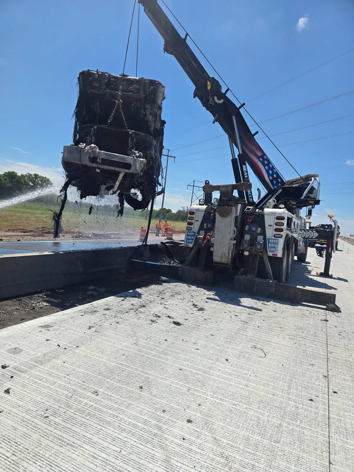 A crane is lifting a car from the ground on a highway.