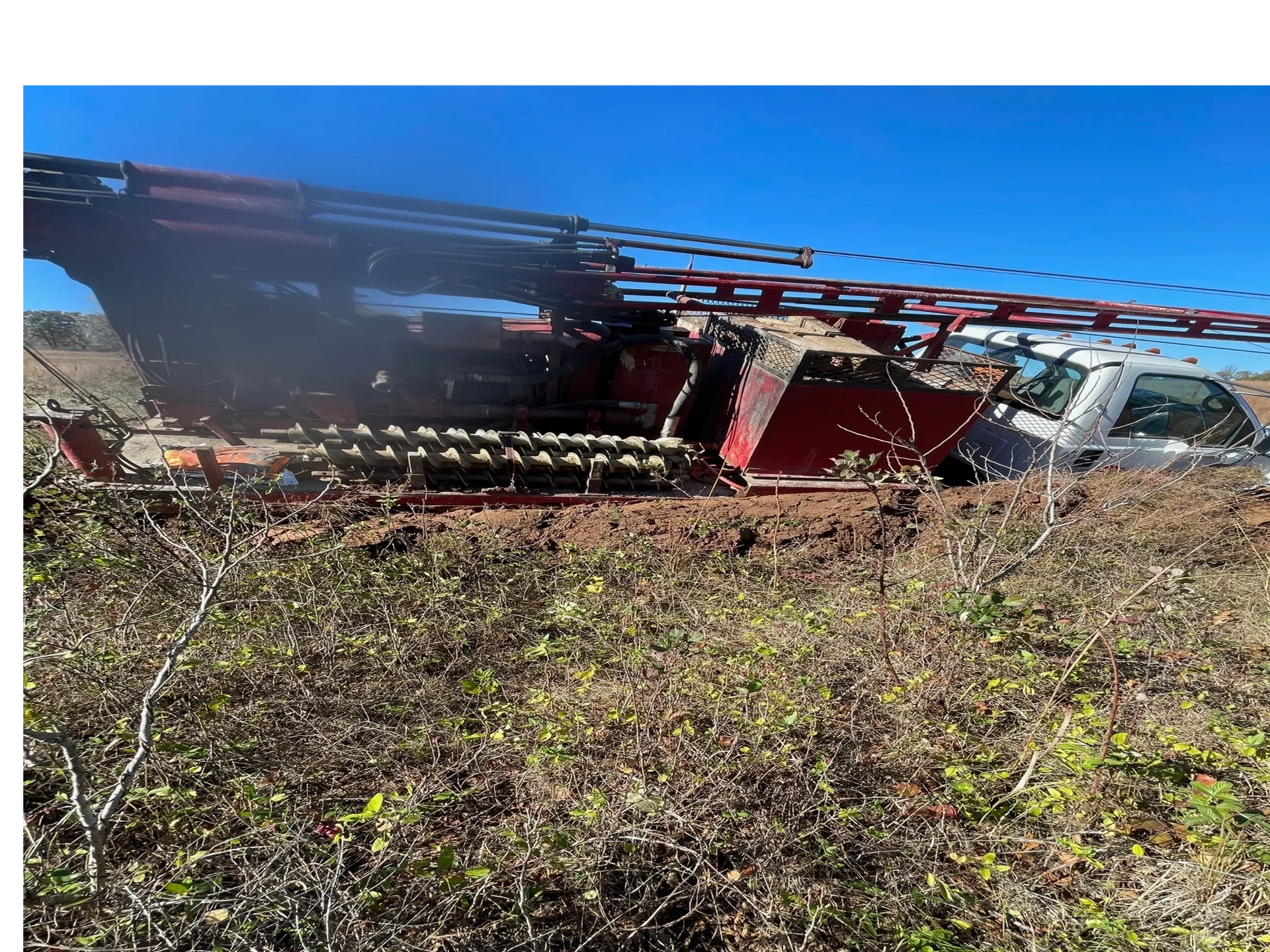 A tractor is sitting in the middle of a field next to a truck.