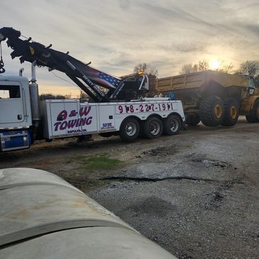 A towing truck is parked next to a dump truck.