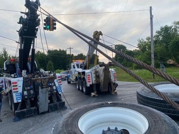 A tow truck is pulling a truck that is stuck on the side of the road.