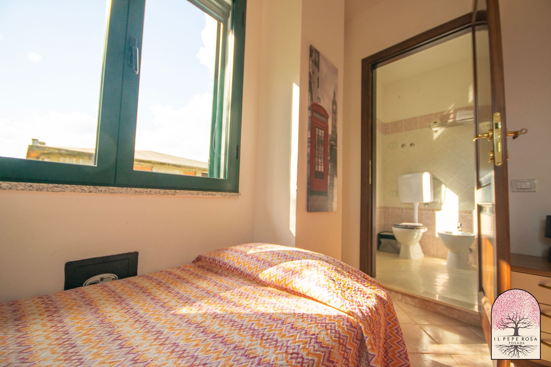 Una camera da letto con un letto, finestra, bagno e toilette.