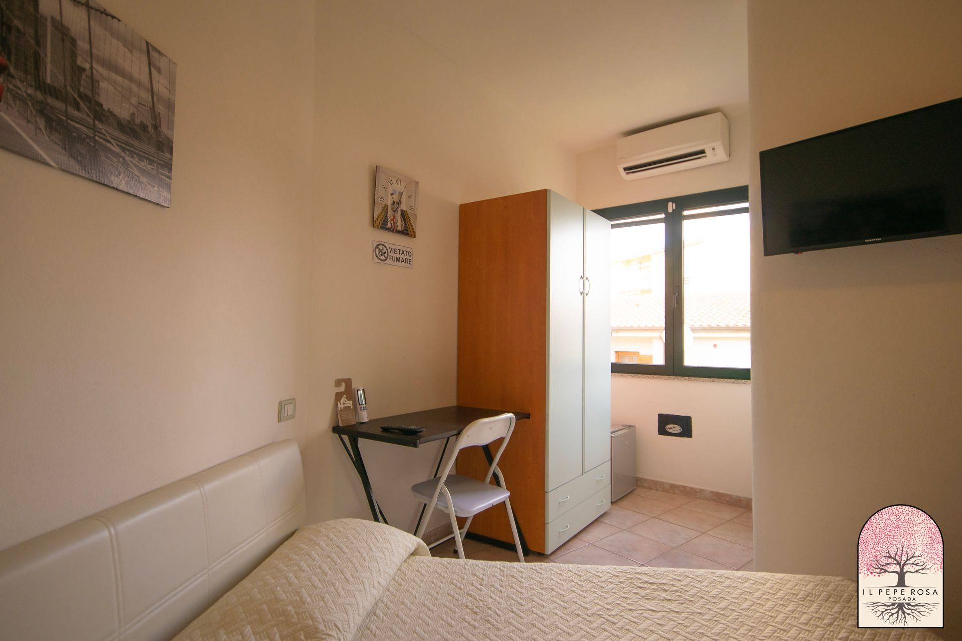 Una camera da letto con un letto, una scrivania, una sedia e una televisione.