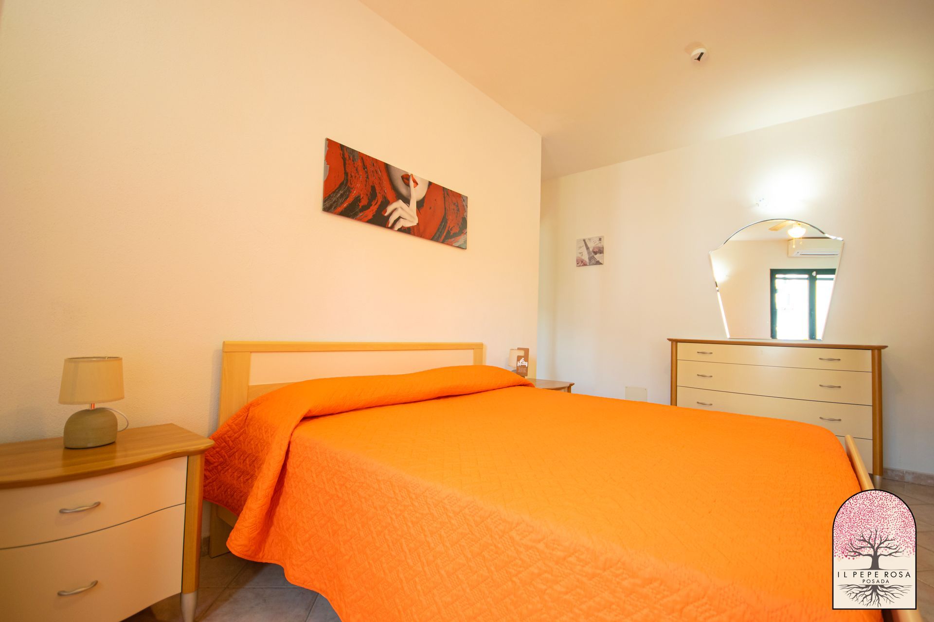 Una camera da letto con un letto arancione e un comò