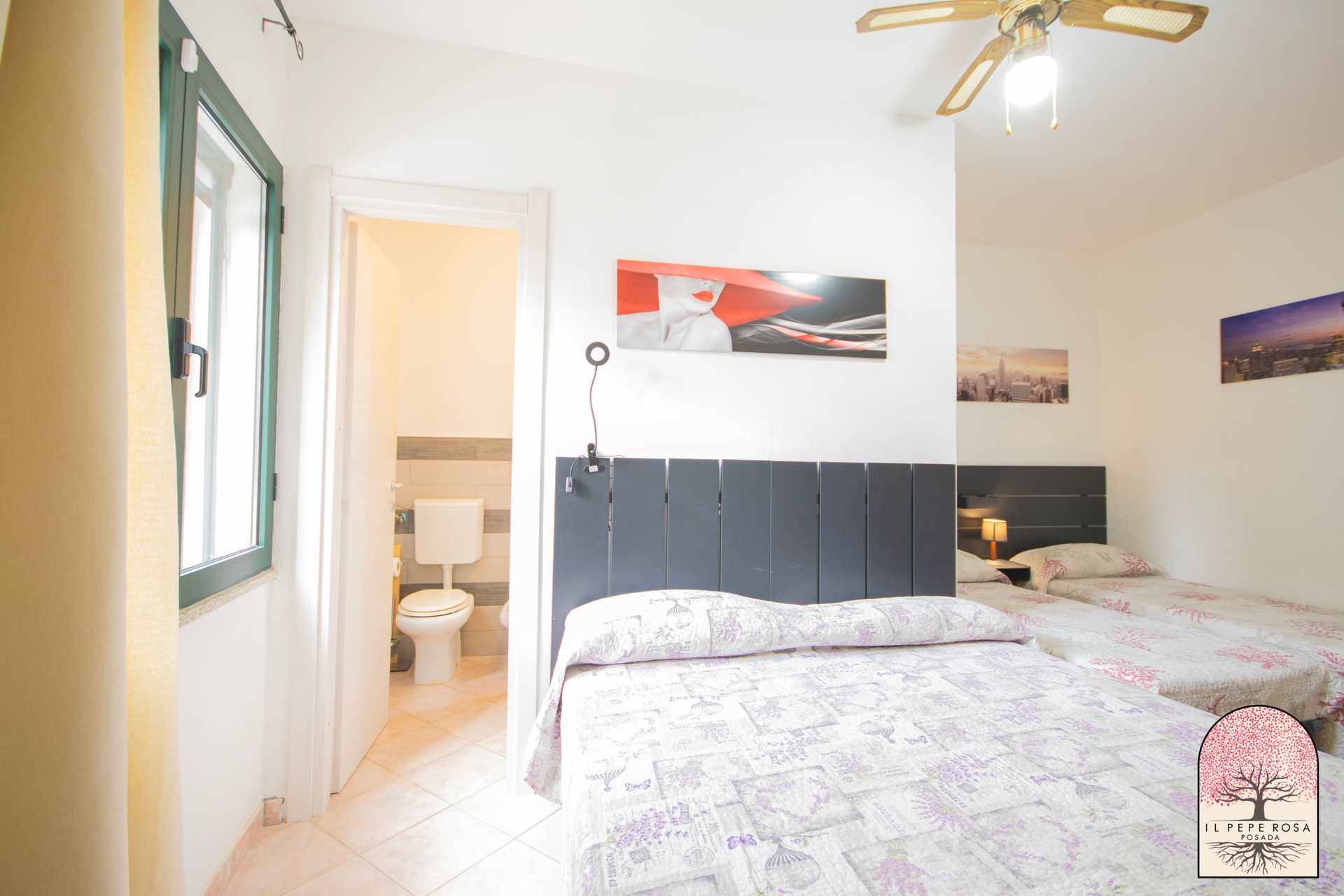 Una camera da letto con due letti, un bagno e un ventilatore a soffitto.