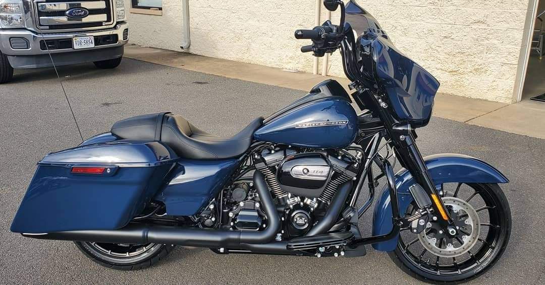 A blue harley davidson street glide is parked in front of a building.