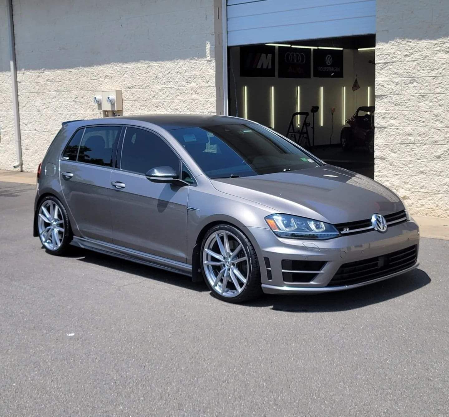 A gray volkswagen golf is parked in front of a garage door