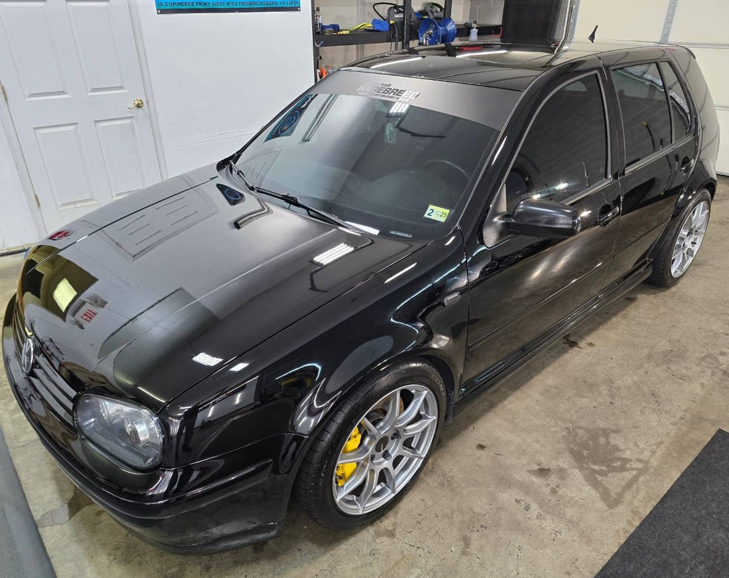 A black volkswagen golf is parked in a garage.
