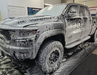 A truck is covered in foam and is sitting on a concrete surface.