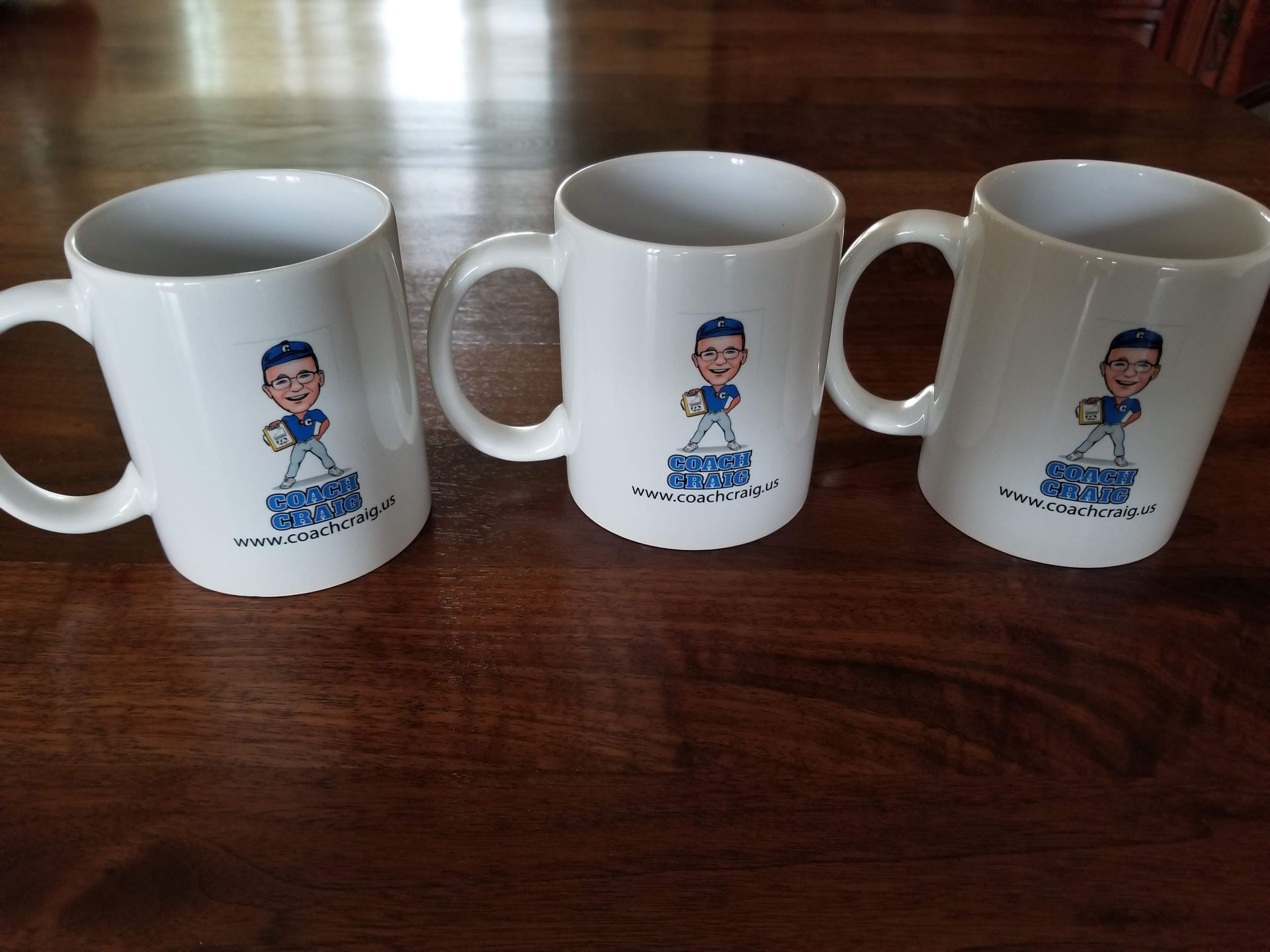 Three coffee mugs with baseball players on them on a wooden table