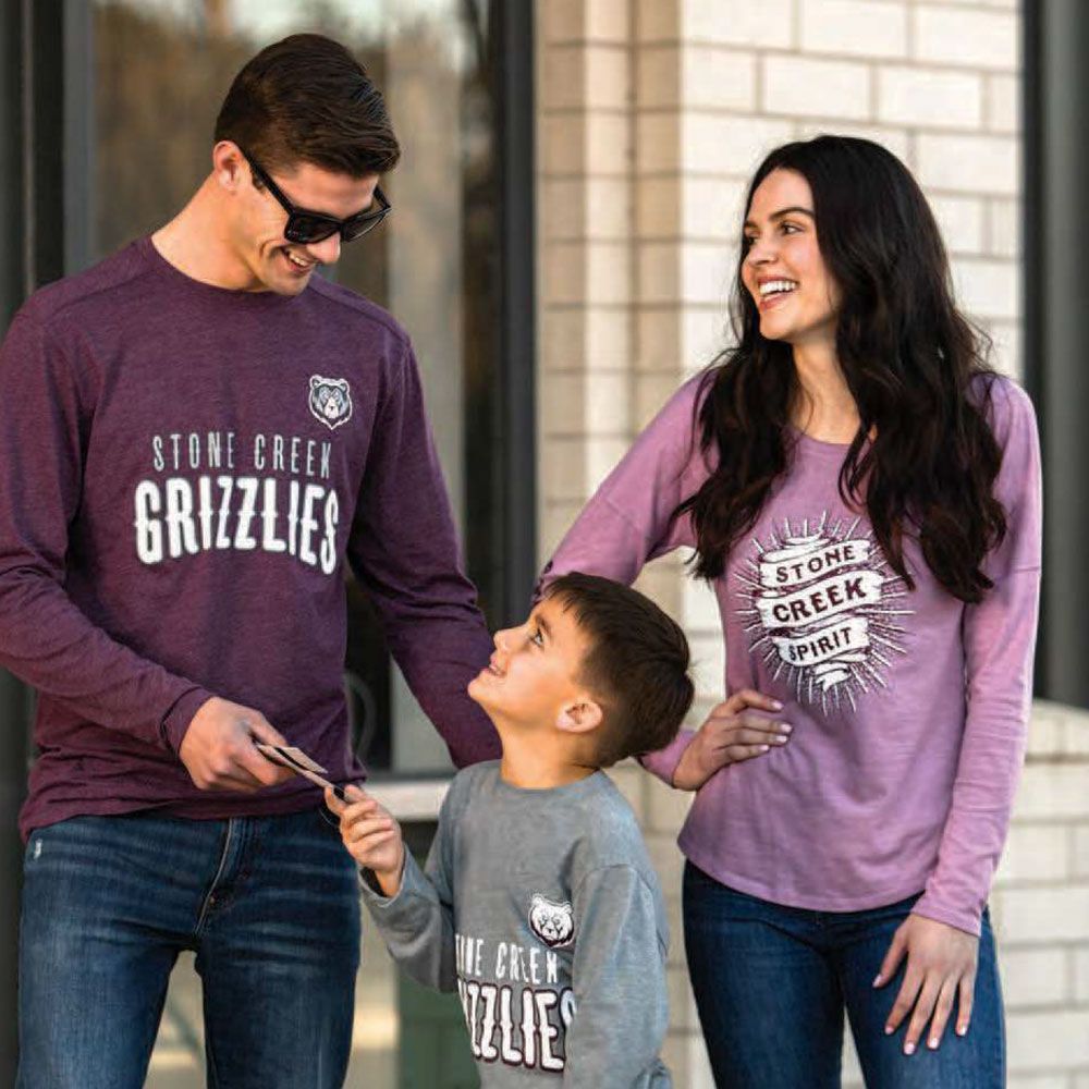 A man and a woman are standing next to a child wearing matching shirts.