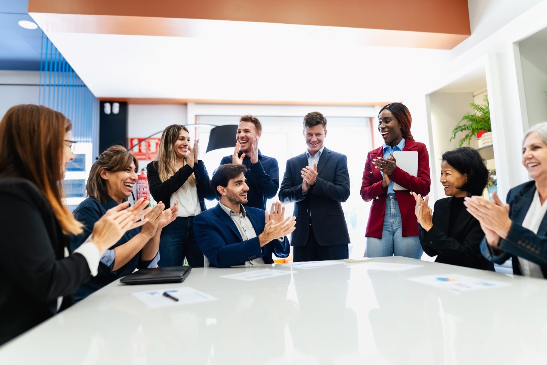 Office team applauding around a conference table, celebrating corporate incentives at a Louisville company