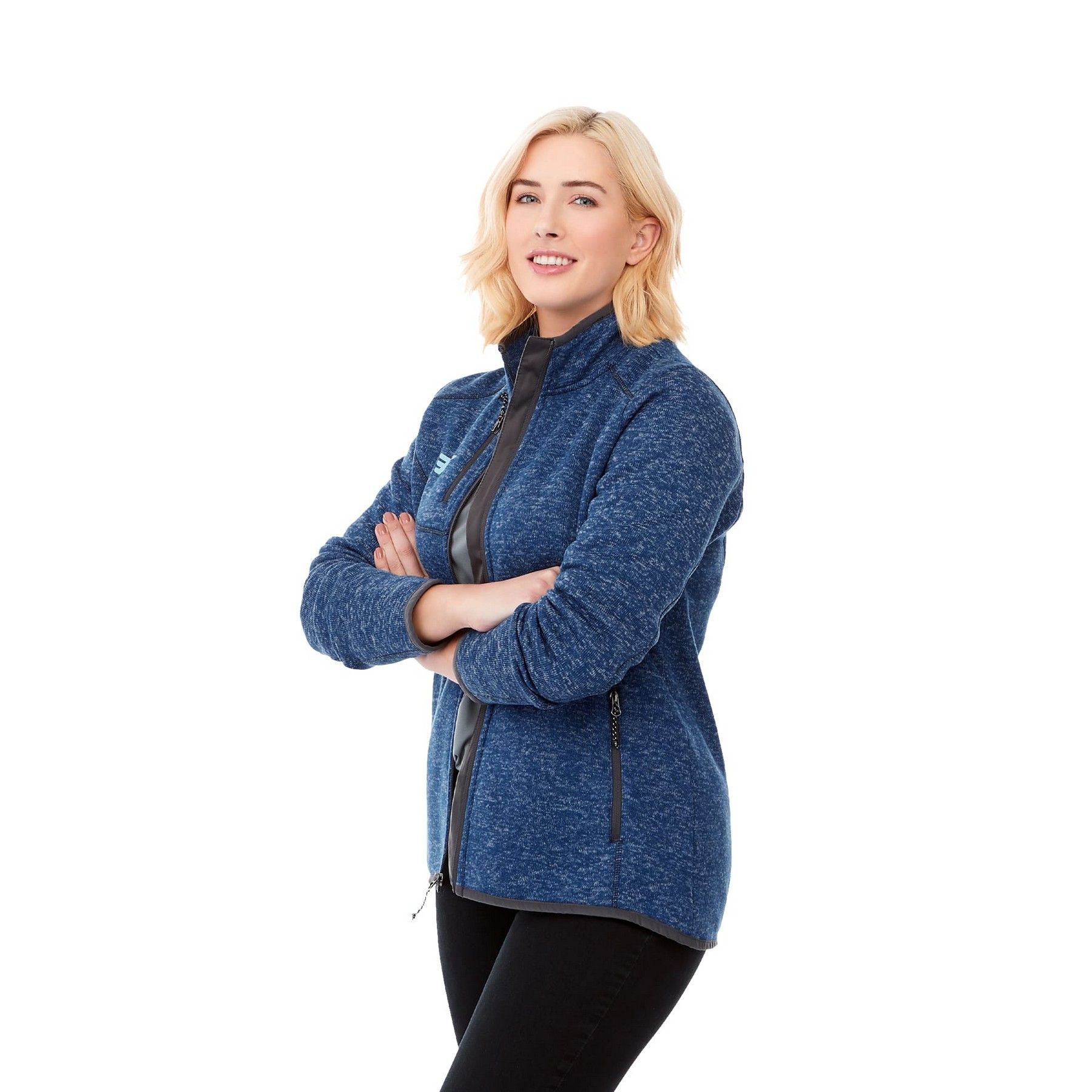 A woman wearing a blue jacket and black pants is standing with her arms crossed.