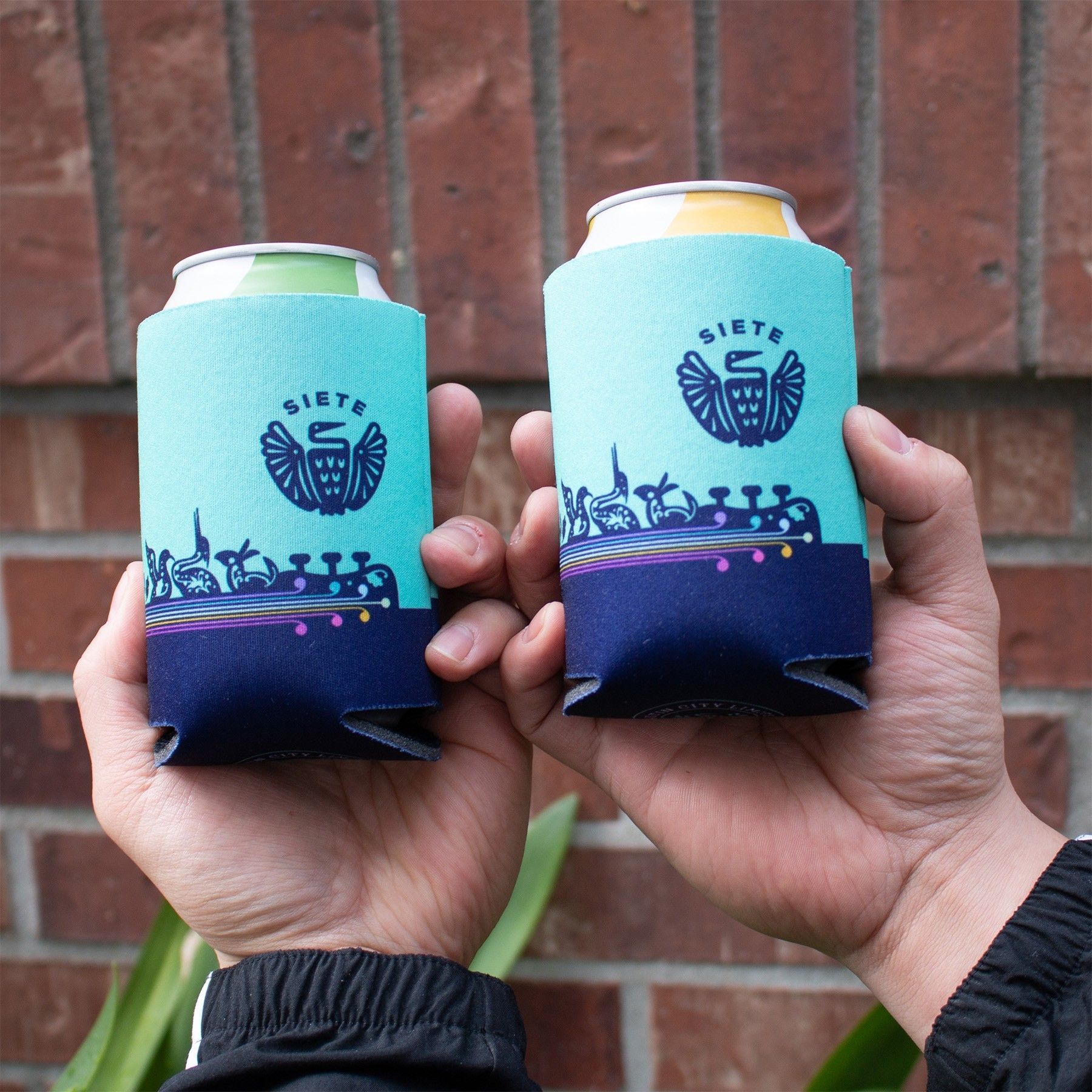 A person is holding two can holders in their hands