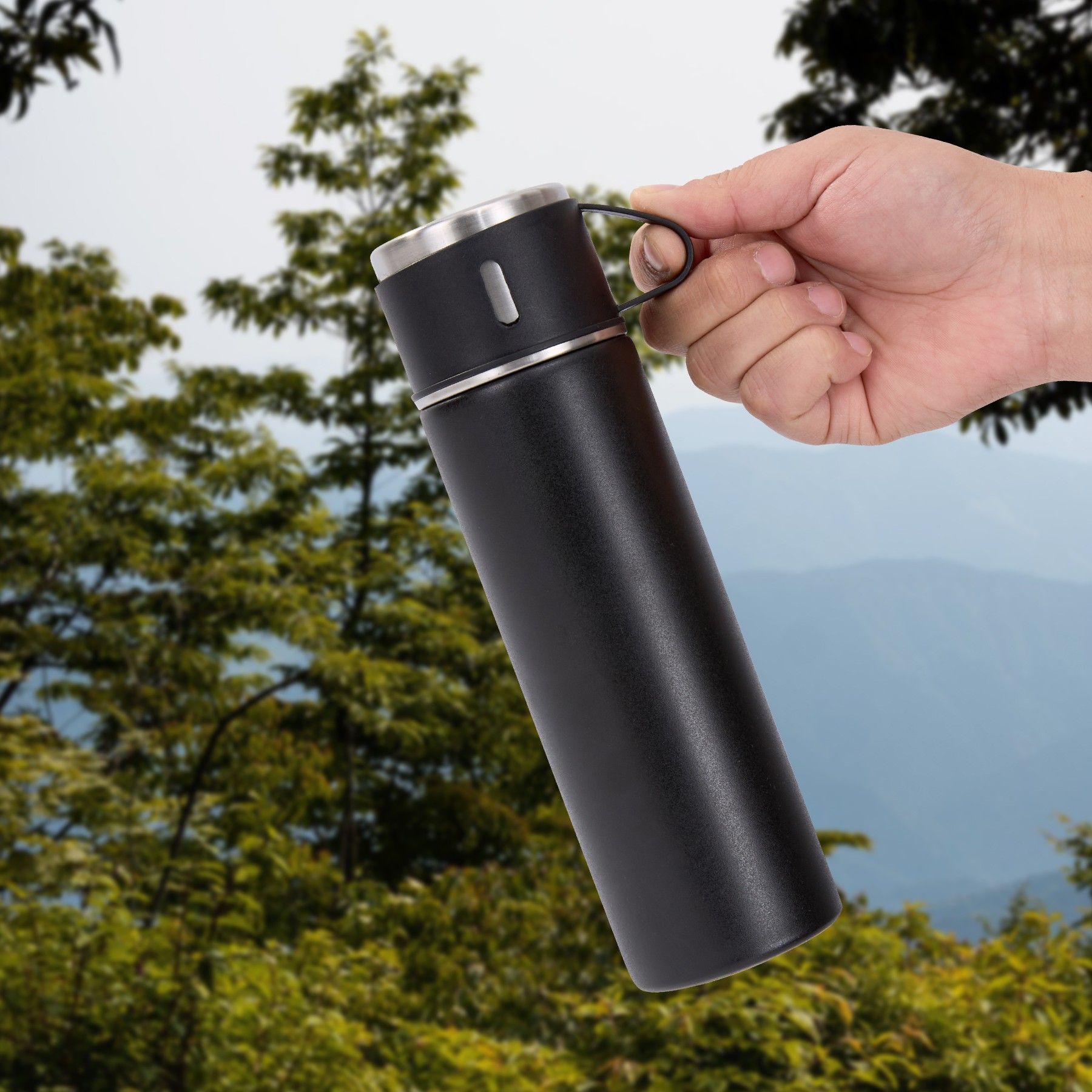 A person is holding a black bottle with a handle in their hand.