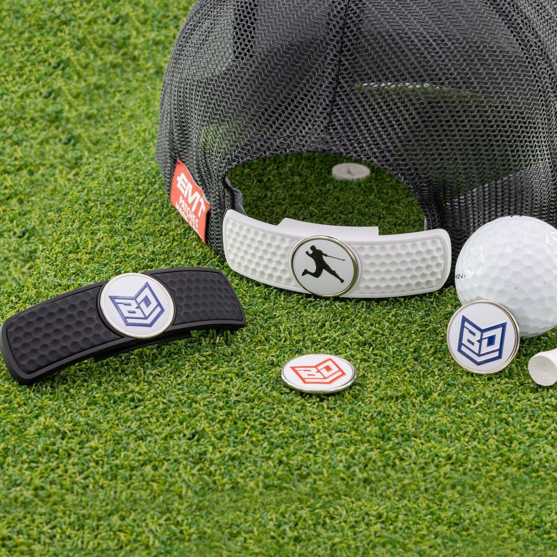 A hat and golf balls are sitting on top of a lush green field.