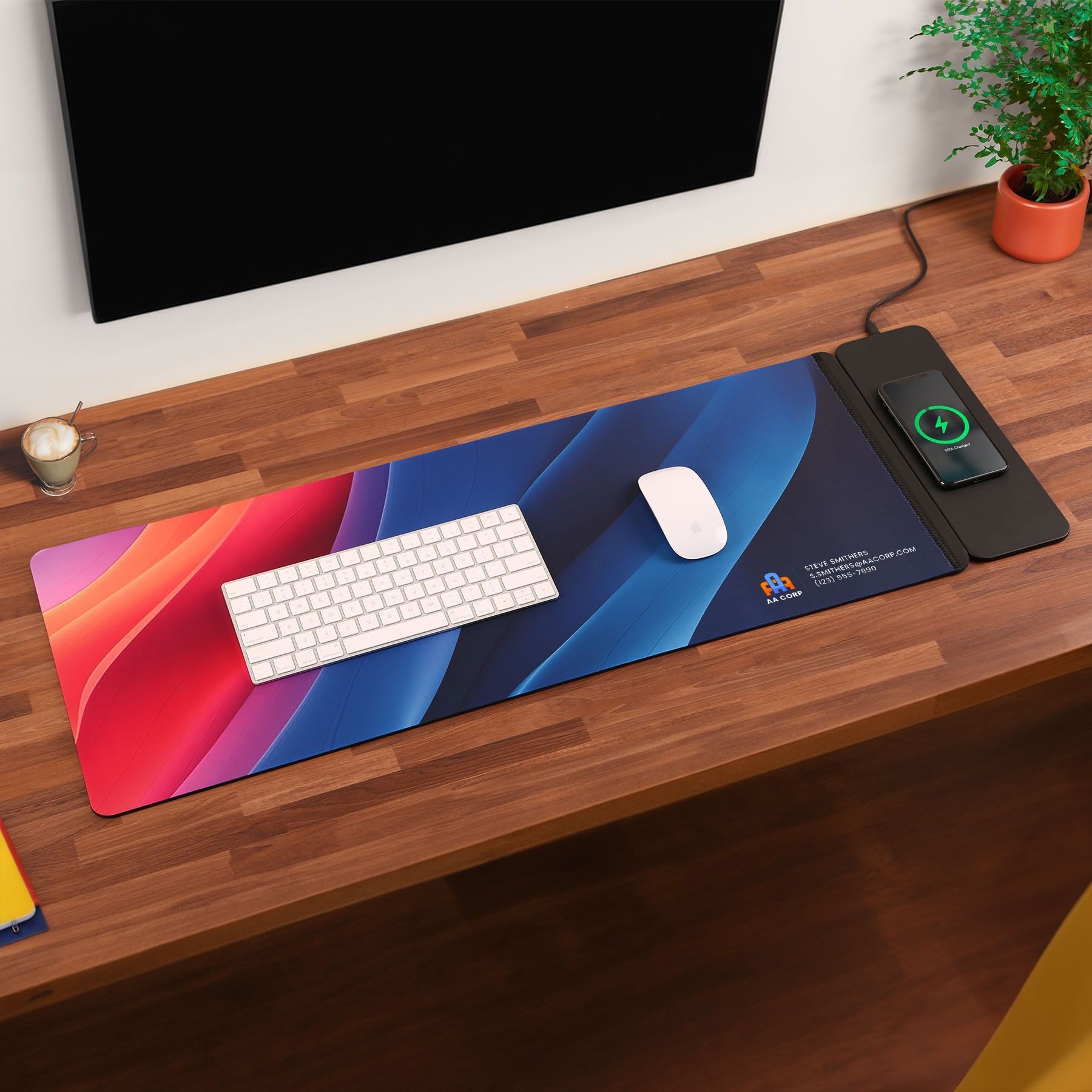 A keyboard and mouse are on a colorful mouse pad on a wooden desk.