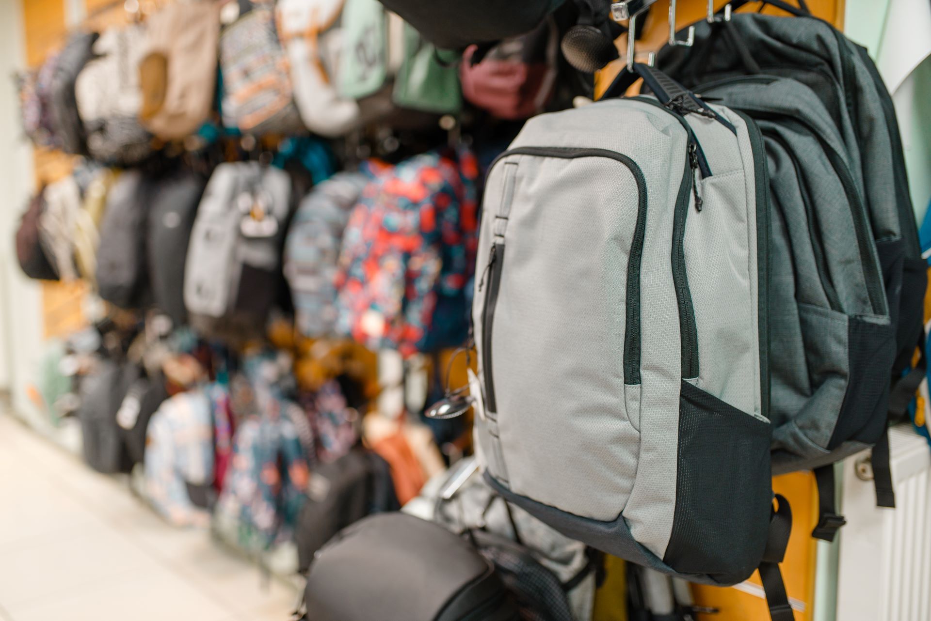 A row of backpacks hanging on a wall in a store.