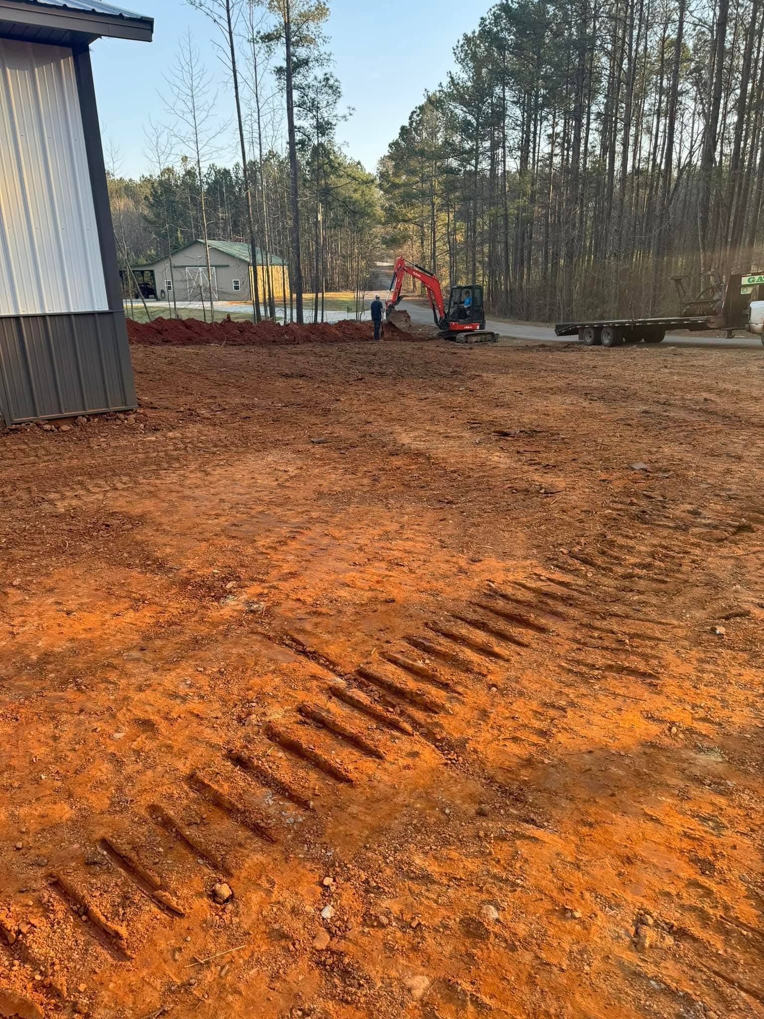 A bright, orange-dirt construction site with a distant red excavator and a building structure on the left.