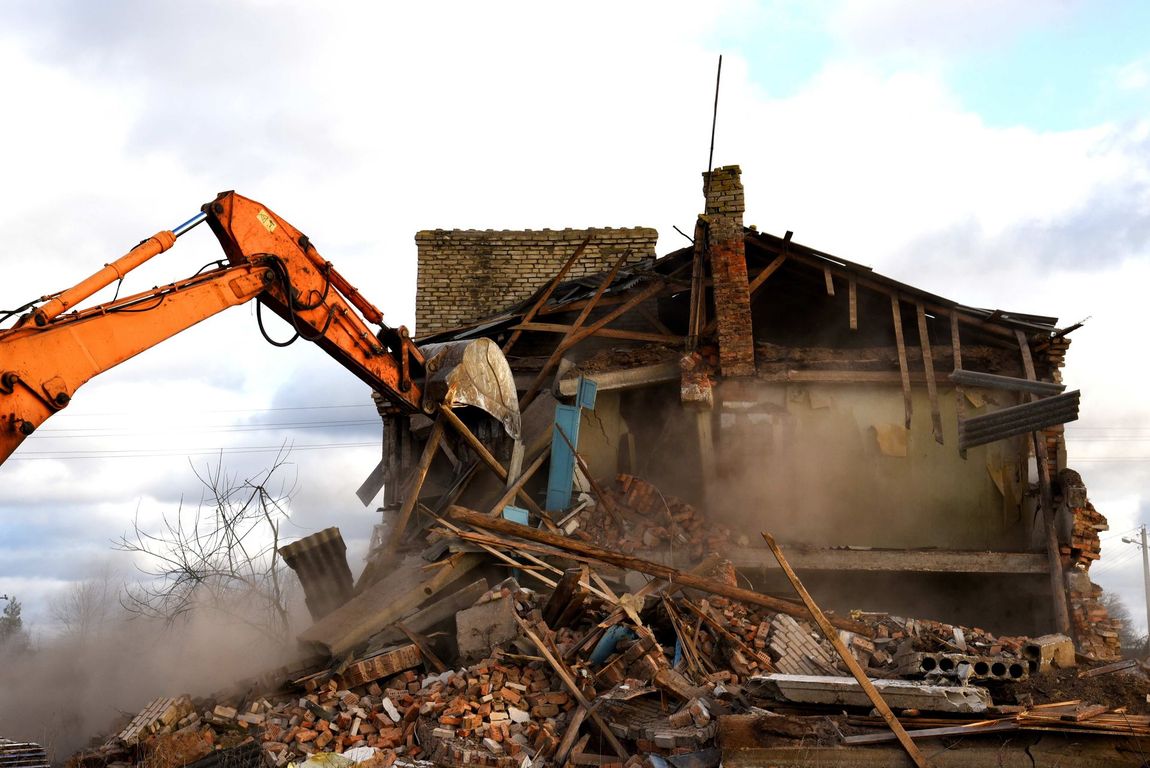 a large orange excavator is demolishing a house