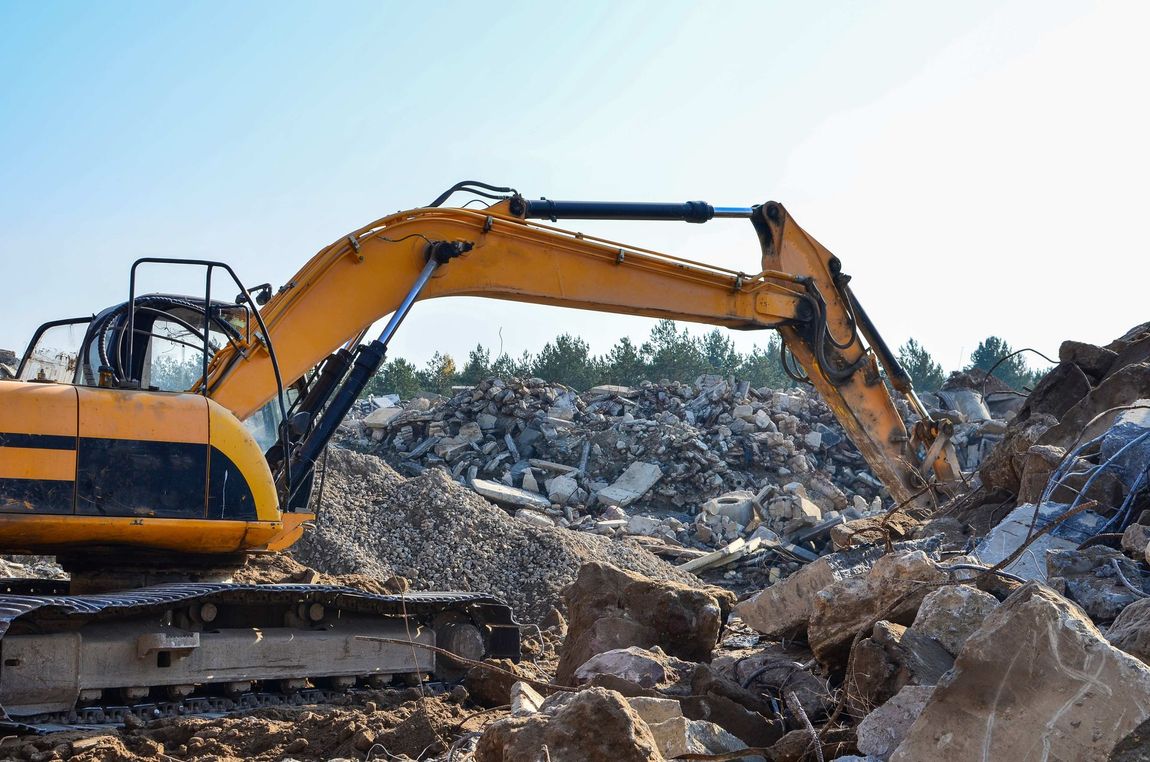 a yellow excavator is working on a pile of rocks