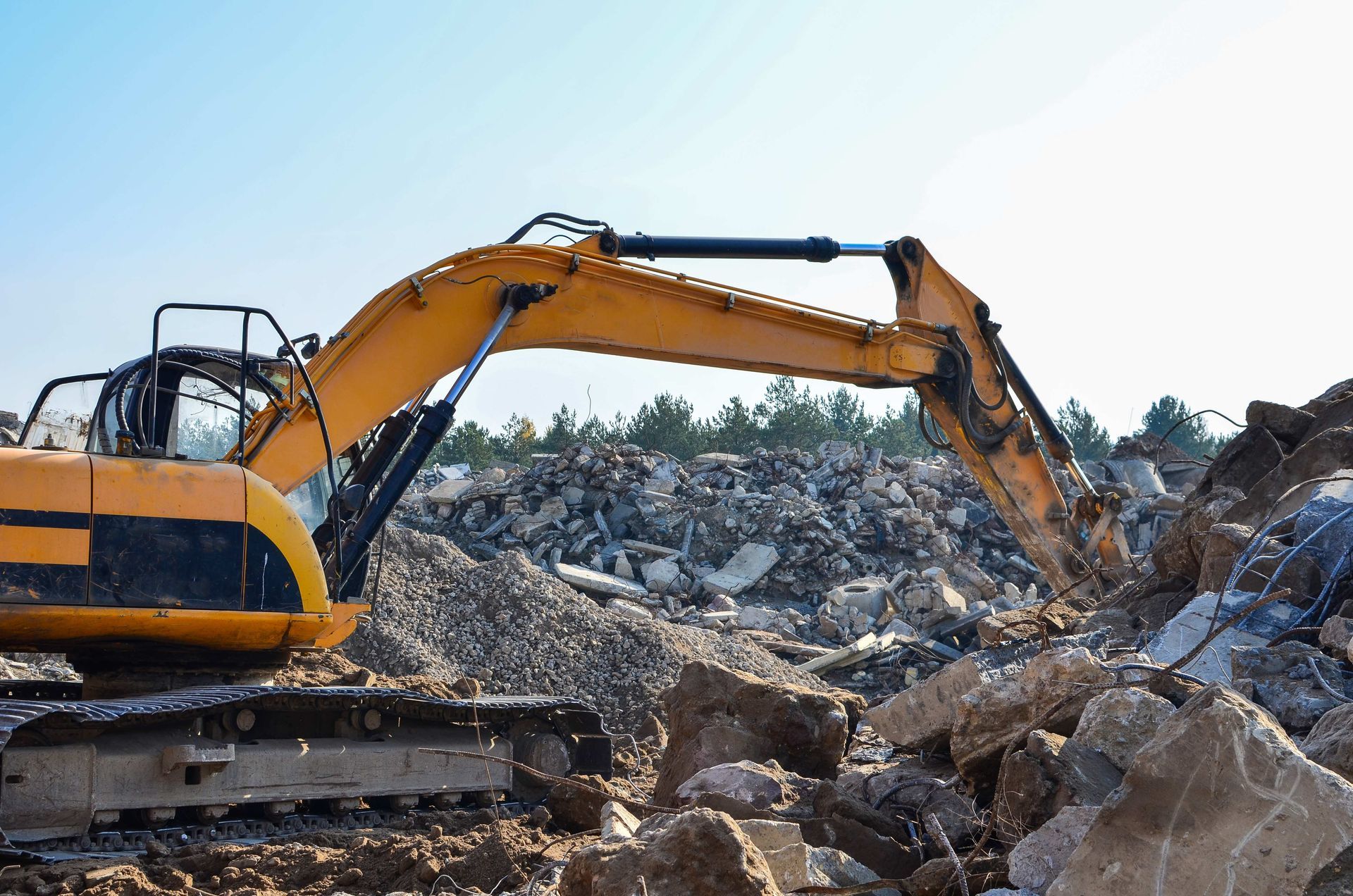 a yellow excavator is working on a pile of rocks
