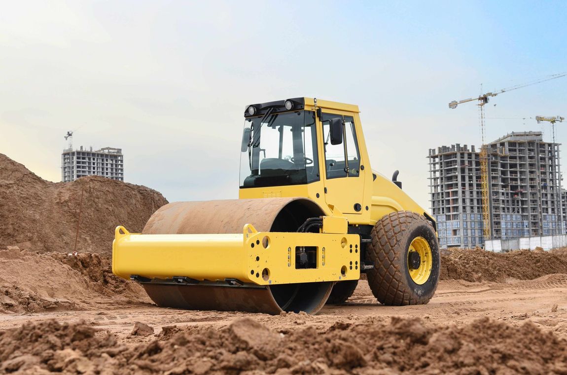 a yellow roller is sitting in the dirt on a construction site