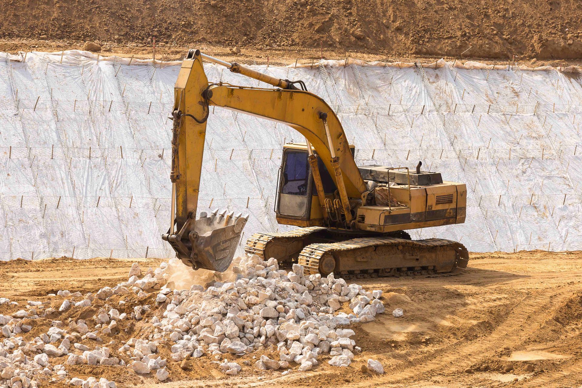 a yellow excavator is moving dirt and rocks on a construction site