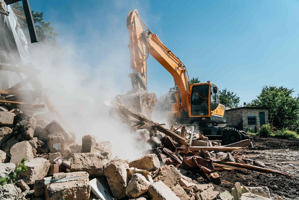 a yellow excavator is demolishing a building on a construction site