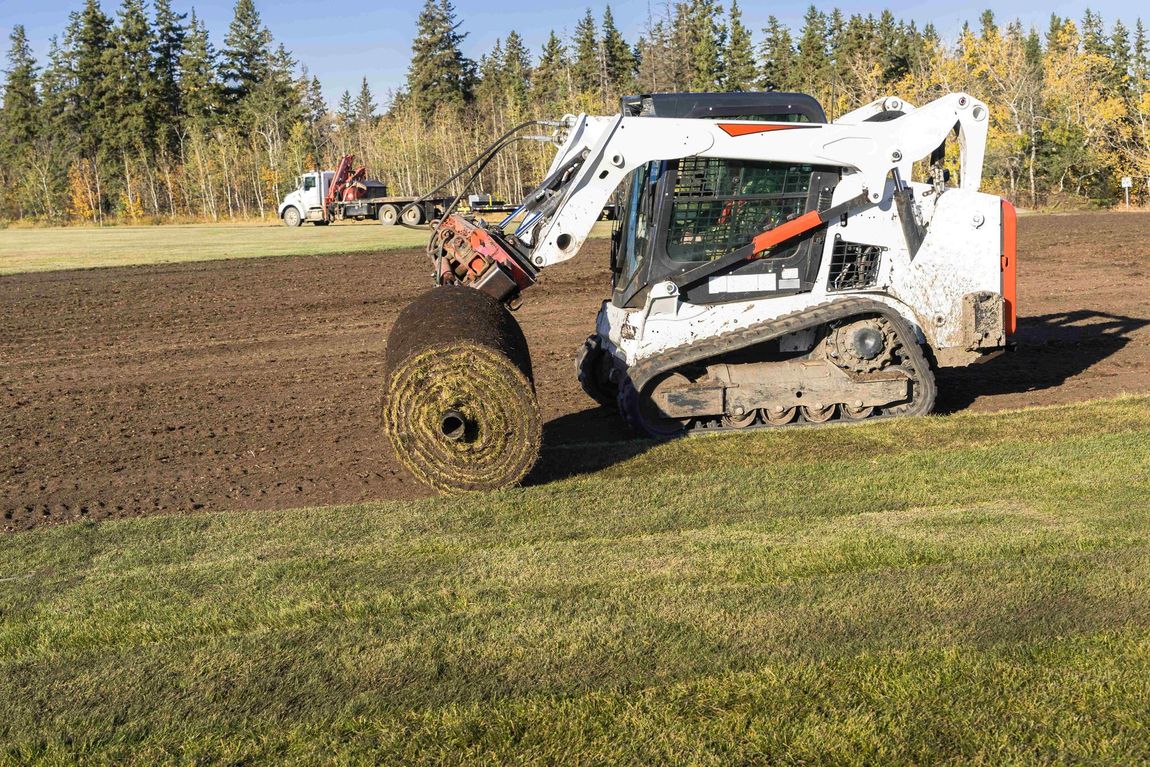 a bulldozer is rolling a roll of grass in a field