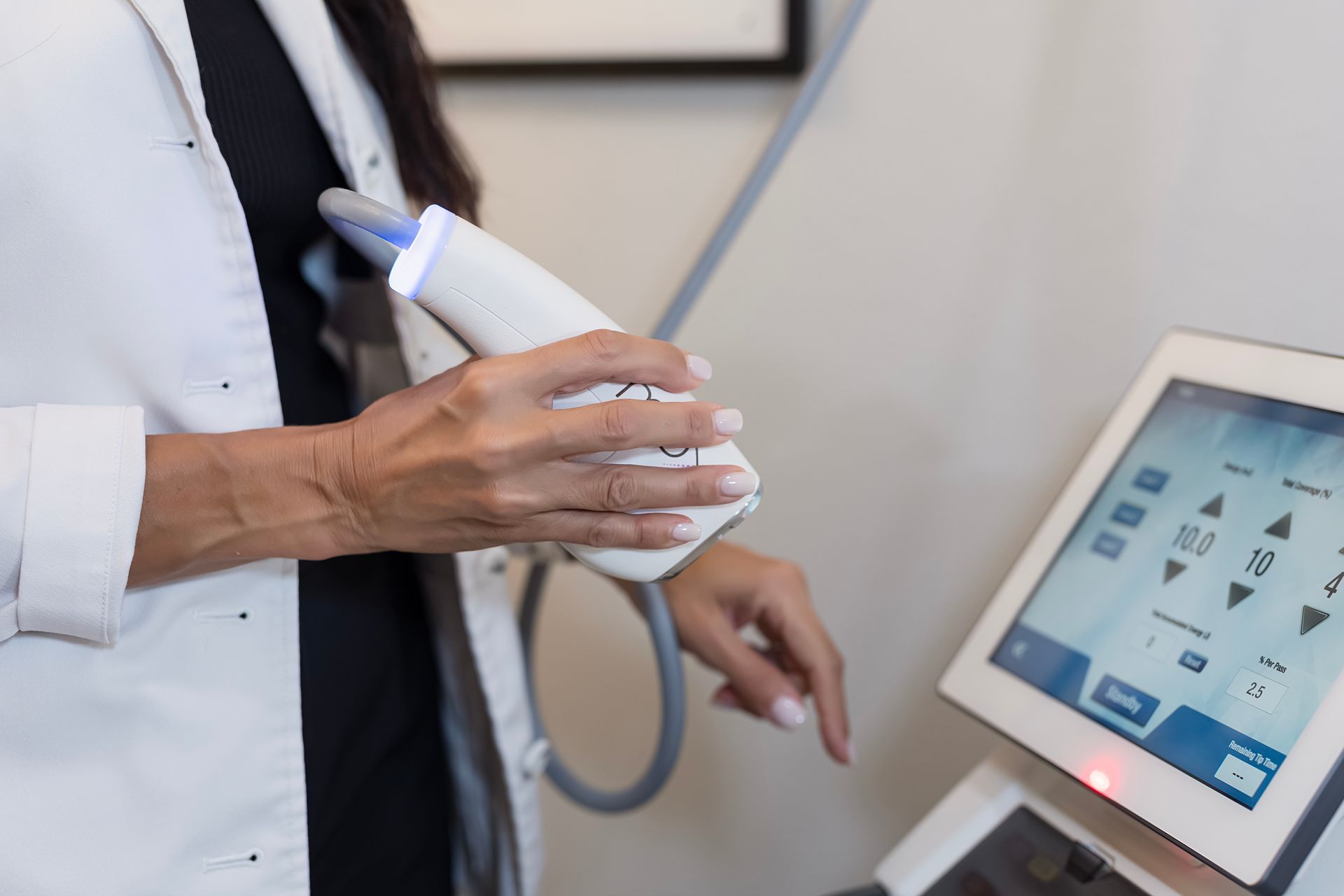 A woman in a lab coat is holding a machine in her hands.