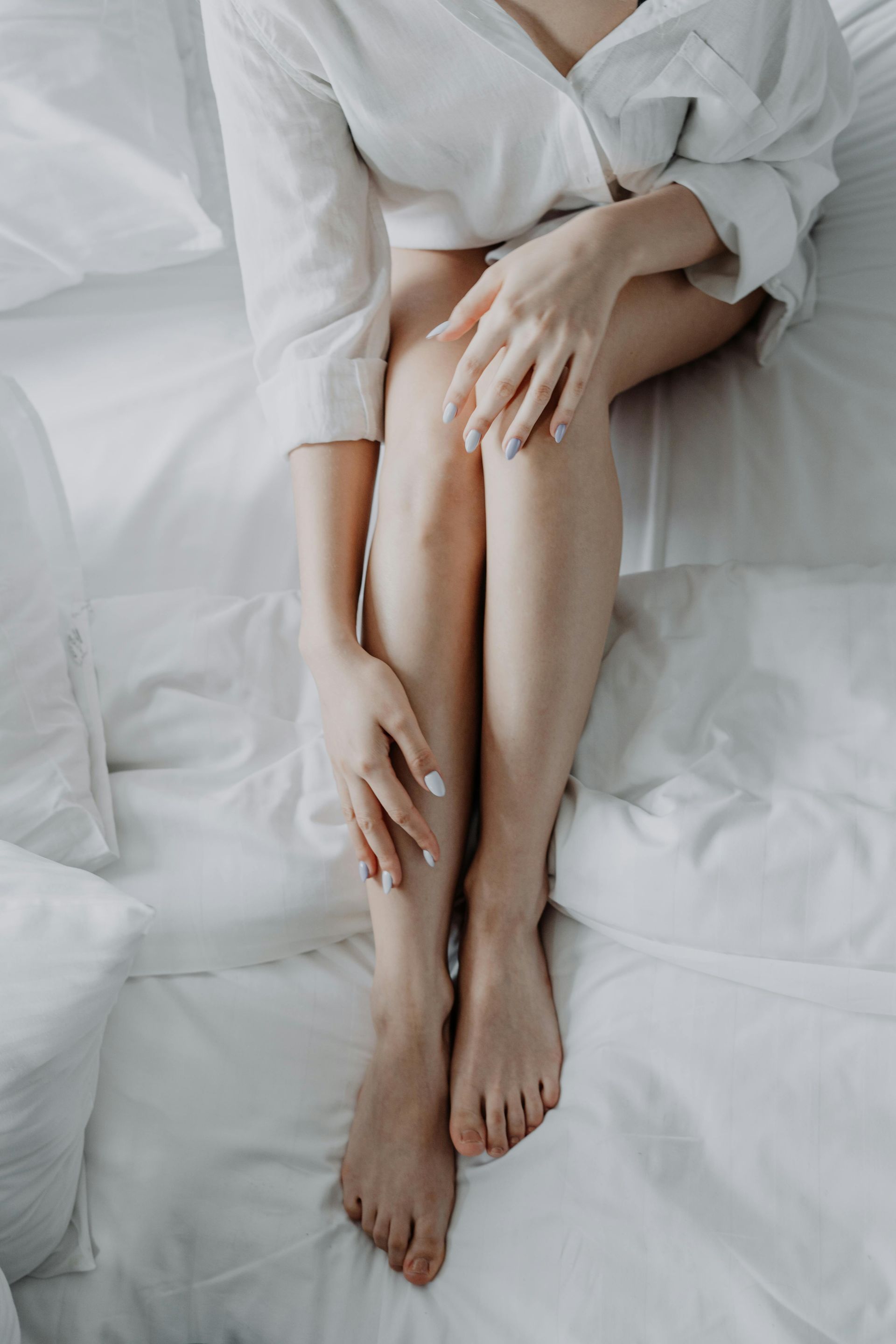 A woman is sitting on a bed with her legs crossed.
