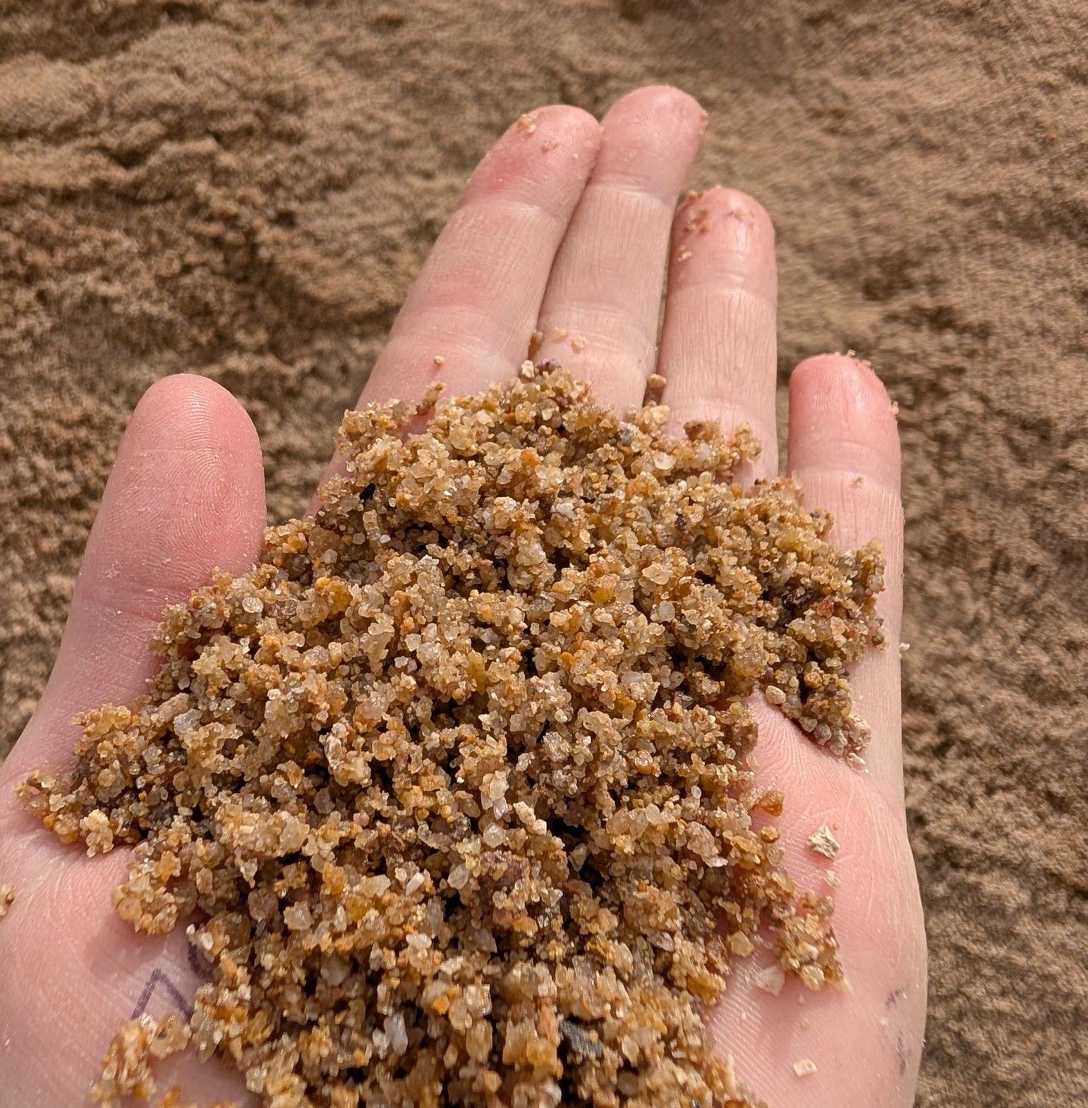 Hand Holding a Pile of Brown Sand — Campbell's Truck and Bobcat and Landscape Supplies In Gympie, QLD