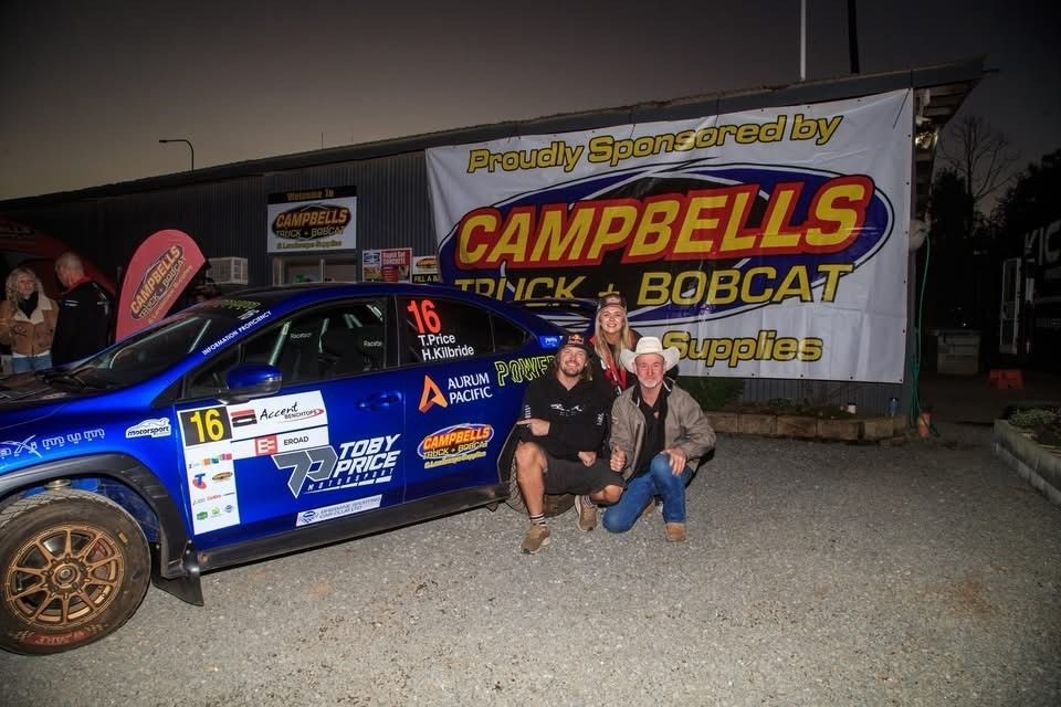 Blue Rally Car With Three People Posing in Front of a Banner — Campbell's Truck and Bobcat and Landscape Supplies In Gympie, QLD