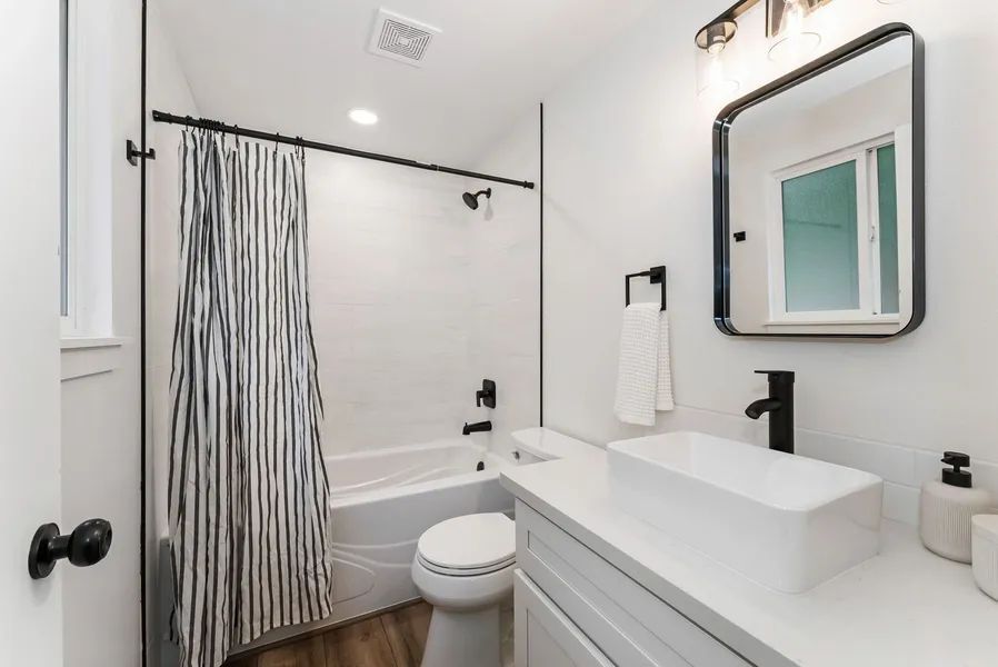 A bathroom with a toilet , sink , bathtub and shower curtain.