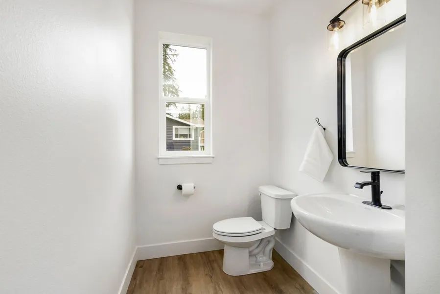 A bathroom with a toilet , sink and mirror.