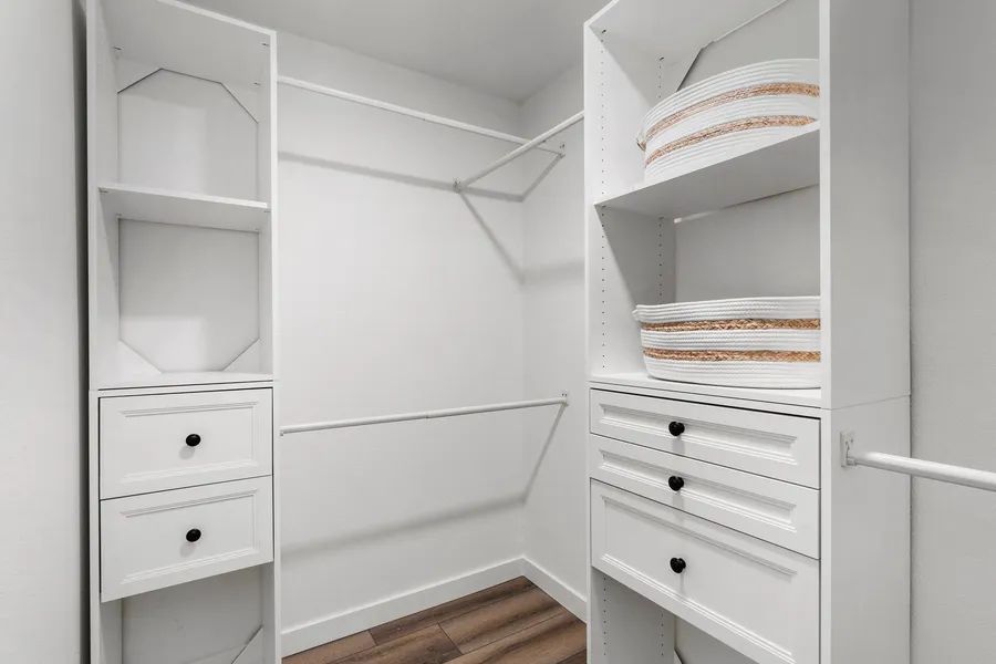 A walk in closet with lots of shelves and drawers.