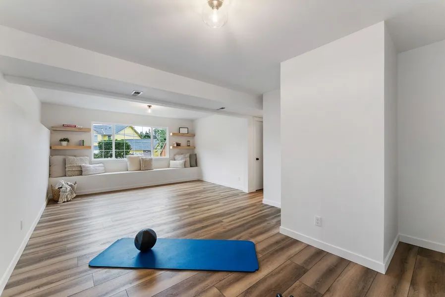 A living room with a blue yoga mat and a ball on the floor.